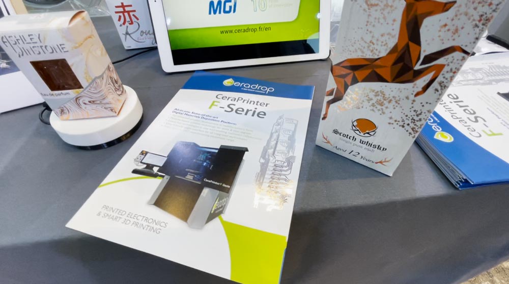 brochures for Ceradrop's CeraPrinter F-Series, on a table with embellished samples on MGI Digital Technology's digital press