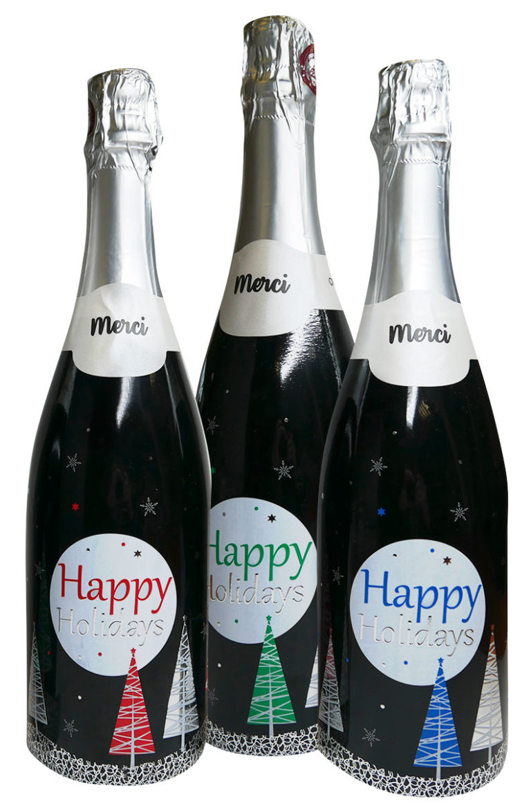Trois sleeves pour du champagne avec des sapins colorés et le texte happy holidays, en dorur argentée et du vernis, réalisées sur une presse MGI Digital Technology